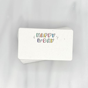 May include: A stack of white cards with the text "HAPPY B-DAY" in colorful letters.