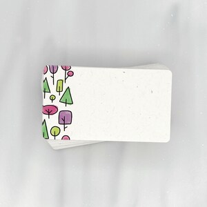 May include: A stack of white note cards with a colorful pattern of trees and flowers on the left edge. The cards are blank on the right side.