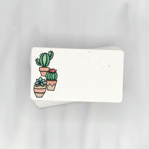 May include: A stack of white note cards with a green, pink, and brown cactus illustration on the front.