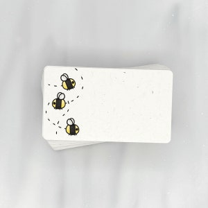 May include: A stack of white note cards with a simple black and yellow bee design. The bees are flying in a line with a dotted line behind them.