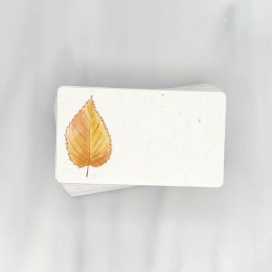 May include: A stack of blank cards with a single yellow leaf printed on the top card.