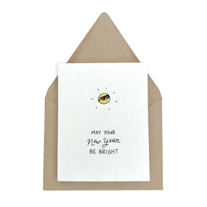 May include: A white card with a yellow sun wearing sunglasses and the text "May your New Year be bright".