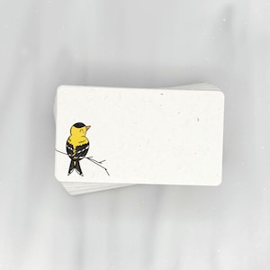 May include: A stack of blank white note cards with a small black and yellow bird illustration on the front.