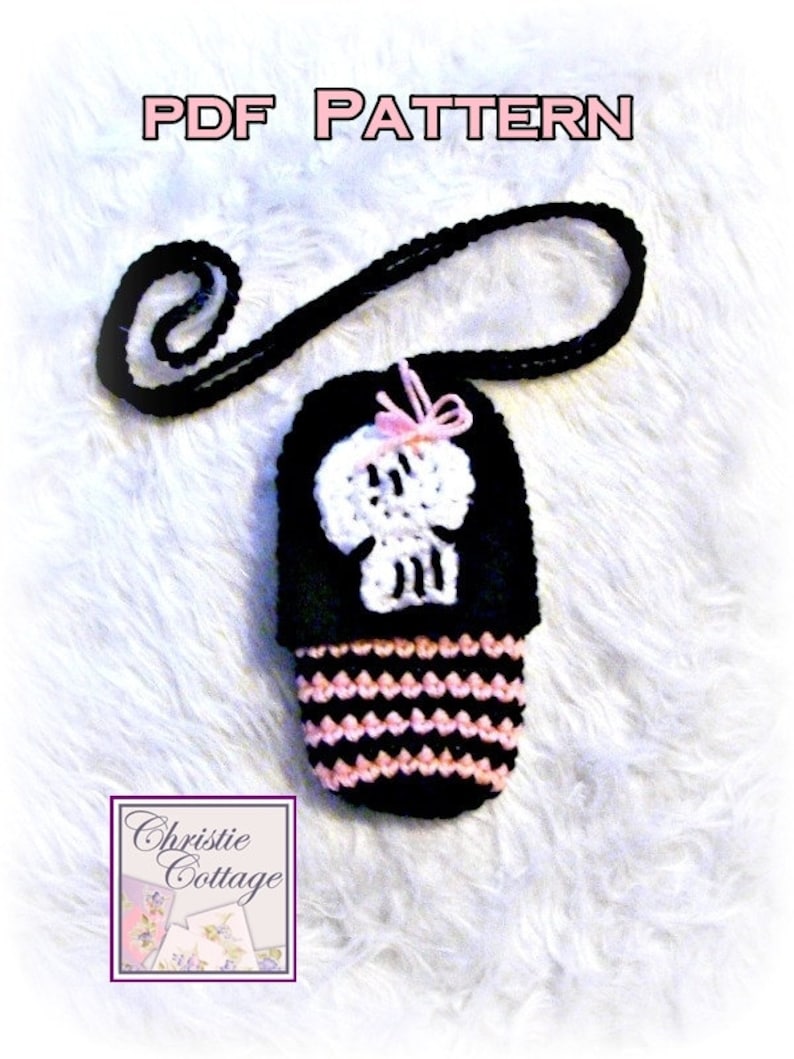 May include: A black and pink crocheted skull-shaped phone case with a black strap. The case has a white skull design and a pink bow. The text "PDF PATTERN" is at the top of the image. The text "Christie Cottage" is at the bottom of the image.