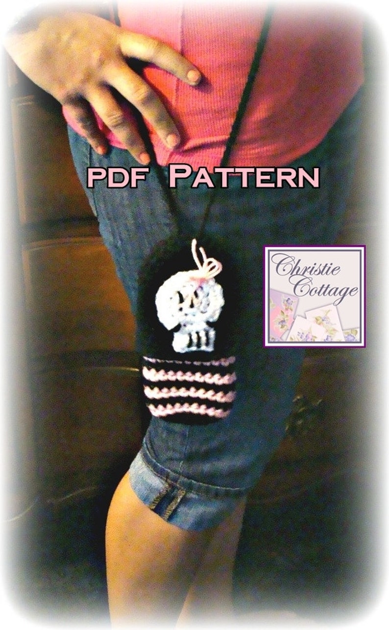 May include: A black and pink crocheted skull bottle cozy with a pink bow. The cozy is hanging from a black strap. The text "PDF PATTERN" is written in pink letters on a blue background. The text "Christie Cottage" is written in white letters on a purple background.
