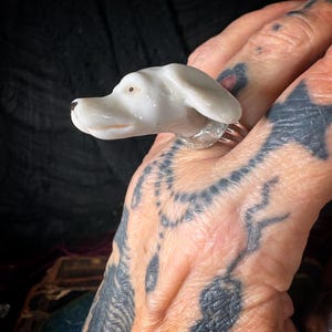 Peut inclure: Bague t&ecirc;te de chien en c&eacute;ramique blanche avec un anneau argent&eacute;. La t&ecirc;te de chien est d&eacute;taill&eacute;e avec un nez noir et un petit point marron pour l'&oelig;il. Un bijou unique.