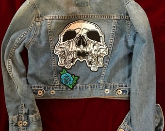 May include: A blue denim jacket with a white skull patch and a blue rose patch on the back.