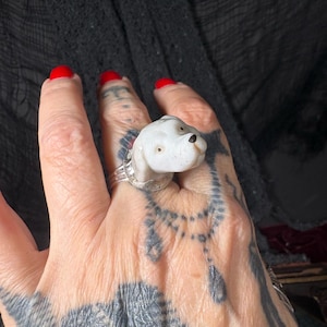 Peut inclure: Bague en c&eacute;ramique blanche repr&eacute;sentant un chien, avec un anneau argent&eacute;. Le chien a les yeux marron et un nez noir. Un bijou unique.