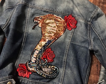 May include: A blue denim jacket with a sequined cobra and red roses embroidered on the back.