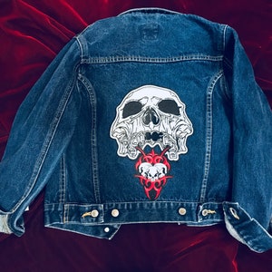 May include: A blue denim jacket with a white skull and red tribal design patch on the back.