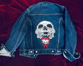 May include: A blue denim jacket with a white skull and red tribal design patch on the back.