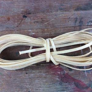 May include: A coil of off-white leather cord, tied with a piece of the same cord.