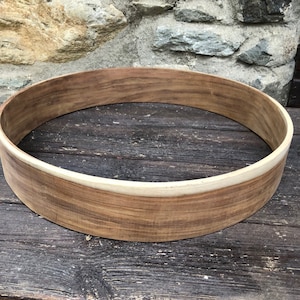 May include: A wooden drum hoop with a natural wood finish and a white inner rim.