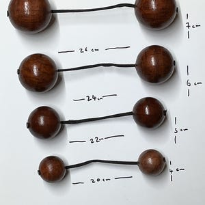 May include: Five sets of wooden beads strung on black cord. The beads range in size from 4 cm to 7 cm in diameter. The cord lengths are marked in centimetres.