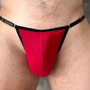 May include: Red thong underwear with black trim and thin black straps. The underwear has a minimalist design and is made of a smooth fabric. The garment is designed for comfort and a sleek look.