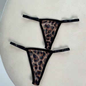 Puede incluir: Dos pares de lencería negra con tejido de malla de estampado de leopardo.