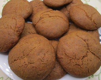 May include: A plate piled high with several round, brown cookies. The cookies have a cracked surface and a slightly uneven shape. The cookies are a warm, inviting brown color, suggesting a baked treat.