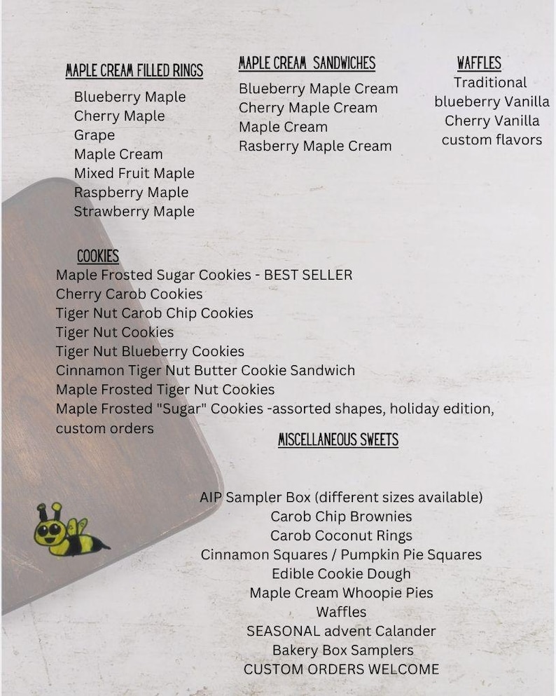 May include: A menu list featuring Maple Cream Filled Rings, Maple Cream Sandwiches, Waffles, Cookies, and Miscellaneous Sweets. The text includes various flavors like Blueberry Maple, Cherry Carob, and Tiger Nut. A small yellow bee icon is visible.