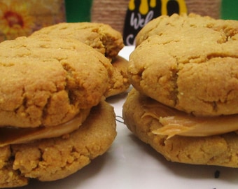Könnte beinhalten: Drei Erdnussbutterkekse mit Erdnussbutterfüllung. Die Kekse sind goldbraun und haben eine leicht raue Textur.