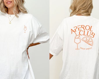 Peut inclure: T-shirt blanc surdimensionné avec un graphique orange d'un verre d'Aperol Spritz et le texte "Aperol Club" et "Feelin' Spritzy" au dos. Le devant du t-shirt présente un petit graphique d'un verre d'Aperol Spritz.