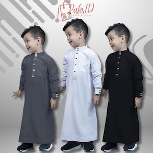 May include: Three young boys wearing long-sleeved shirts with a button-up collar. The shirts are in gray, white, and black. The boys are standing in front of a white background with a gray and white geometric pattern.