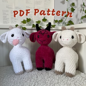 Puede incluir: Tres peluches de cabra de crochet. Uno es blanco, otro es blanco con una lengua rosa y el último es rojo con cuernos negros y un pentagrama en el pecho. Los peluches están sentados sobre una superficie blanca y esponjosa. Patrón PDF.