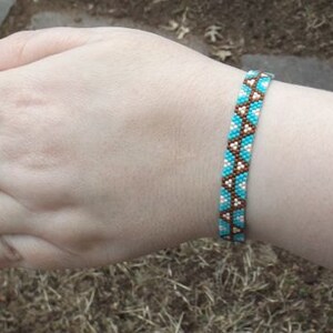 Puede incluir: Un brazalete de cuentas turquesa, blanco y marrón en la muñeca de una persona.