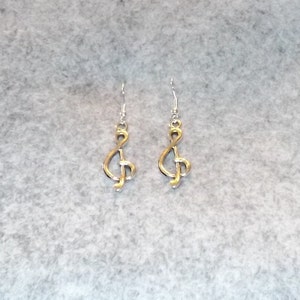 May include: A pair of silver earrings with a gold treble clef design.