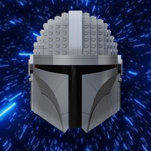 May include: A grey Mandalorian helmet made from interlocking building blocks. The helmet has a T-shaped visor and a distinctive crest. The background is a blue space scene with streaks of light.