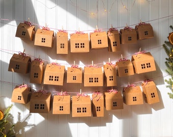 May include: A brown paper advent calendar with 24 small house-shaped boxes hanging from a string. Each box has a number printed on it, from 1 to 24. The boxes are decorated with red and white twine.