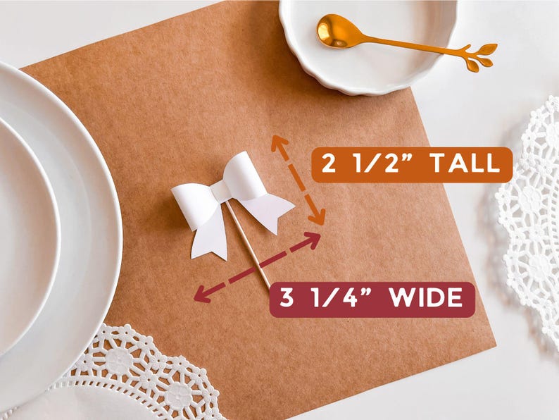 May include: White paper bow with a wooden stick, measuring 2 1/2 inches tall and 3 1/4 inches wide. The bow is on a brown surface.
