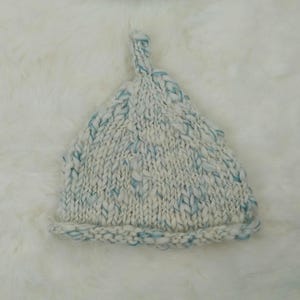 May include: White knitted hat with a blue and white marled yarn. The hat has a pointed top and a folded brim.