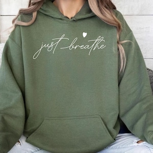 May include: A green hooded sweatshirt with the text "just breathe" in white lettering and a small white heart above the word "breathe".