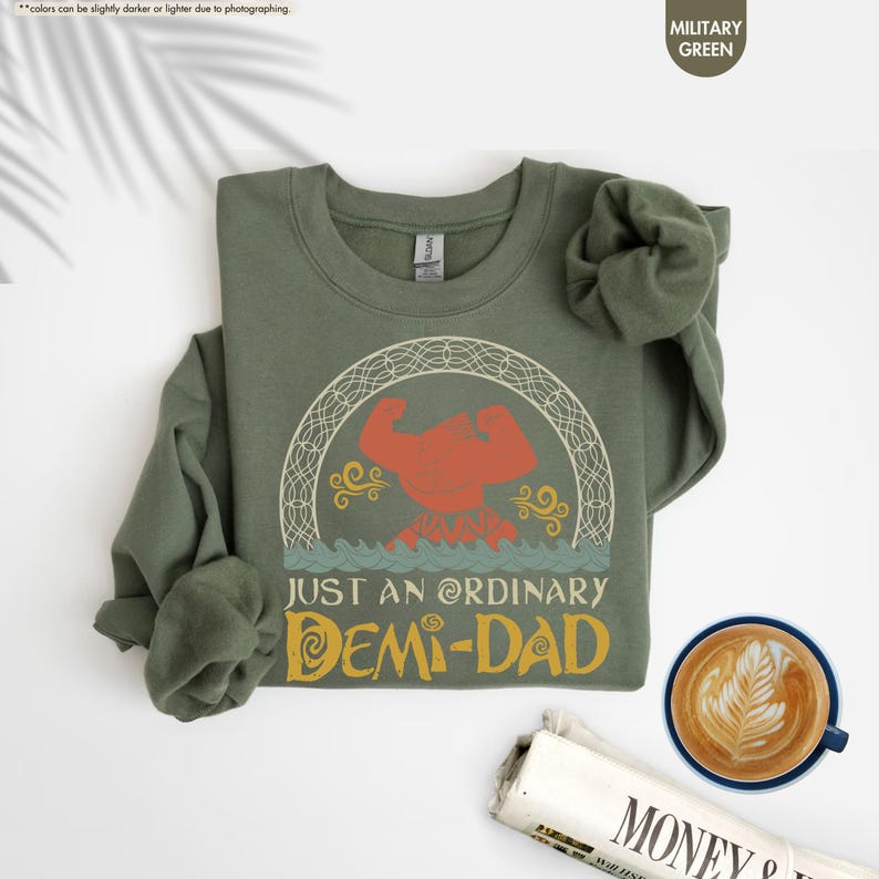 Puede incluir: Una sudadera verde con un gr&aacute;fico de estilo vintage de una figura musculosa con el texto "Just an Ordinary Demi-Dad".