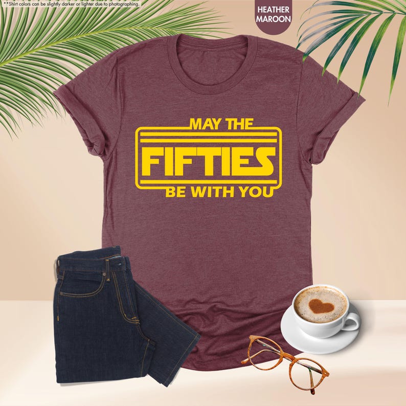 May include: A heather maroon t-shirt with a yellow graphic that says "May the Fifties Be With You".