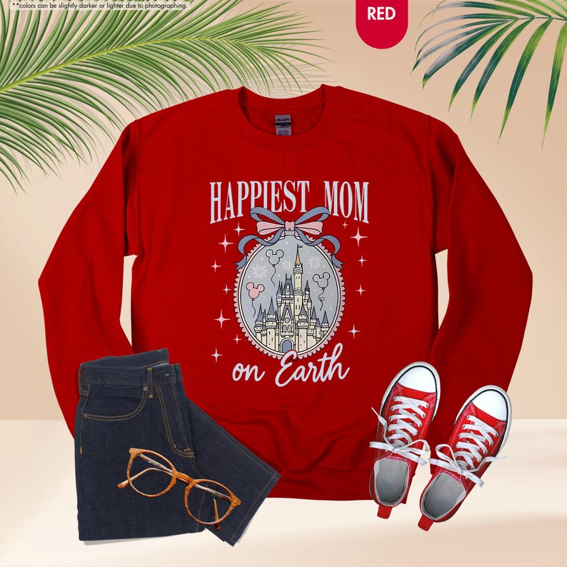 May include: A red sweatshirt with the text "HAPPIEST MOM on Earth" and a graphic of a castle. The image also includes a pair of blue jeans, red sneakers, and eyeglasses.