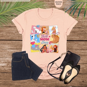Pode incluir: Camiseta rosa com uma colagem de princesas e personagens da Disney, incluindo Ariel, Bela, Pocahontas e Simba. O texto "Best Mom Ever" est&aacute; no centro da colagem.