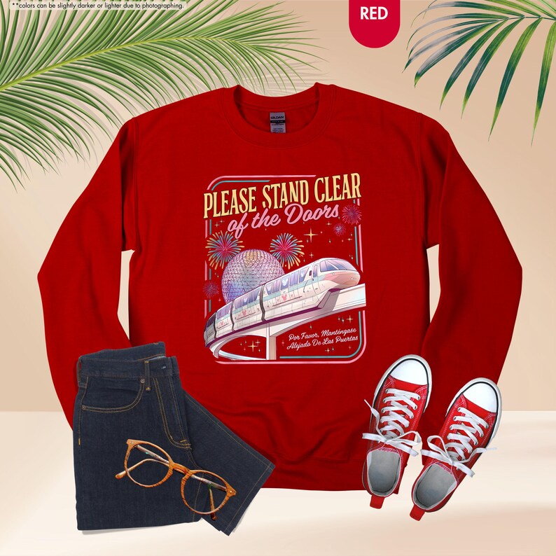 May include: A red sweatshirt with the text "PLEASE STAND CLEAR of the Doors" and a graphic of a monorail and fireworks. The image also includes a pair of blue jeans, gold-rimmed glasses, and red sneakers.