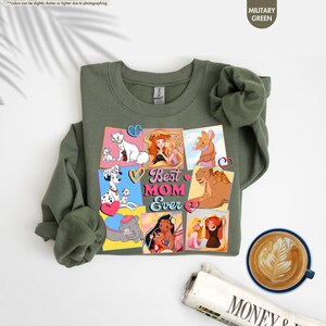 Pode incluir: Uma camisa de moletom verde com uma colagem de personagens de desenhos animados e o texto "Best Mom Ever".