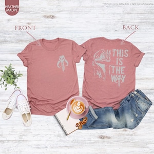 Pu&ograve; includere: Una t-shirt color malva melange con un simbolo mandaloriano sul davanti e il testo "This is the way" con un elmetto mandaloriano sul retro.