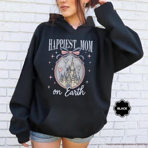 May include: Black hooded sweatshirt with the text "HAPPIEST MOM on Earth" in a decorative font. The design includes a castle, bow, and stars. The word "BLACK" is in a black bubble.