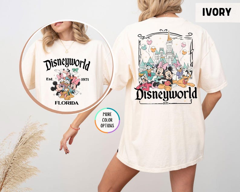 Puede incluir: Camiseta color marfil con dise&ntilde;o de Disney World. El gr&aacute;fico frontal incluye "Disneyworld" sobre personajes de Disney y "Florida Est. 1971." La parte trasera muestra un gr&aacute;fico m&aacute;s grande de Disney World con personajes y el texto "Disneyworld 1971."