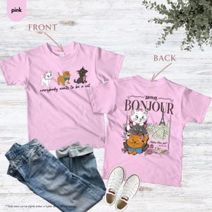 May include: Pink t-shirts with cat graphics. One shirt features three cartoon cats and the text "everybody wants to be a cat." The other shirt has a graphic of three cats with the Eiffel Tower and the word "Bonjour."