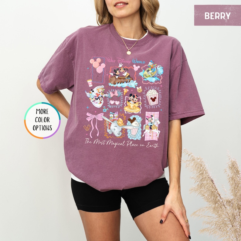 May include: Berry-colored t-shirt featuring a colorful graphic of Disney characters and attractions. The design includes images of Mickey and Minnie Mouse, Dumbo, and other iconic elements. Text on the shirt reads "Walt Disney World" and "The Most Magical Place on Earth."