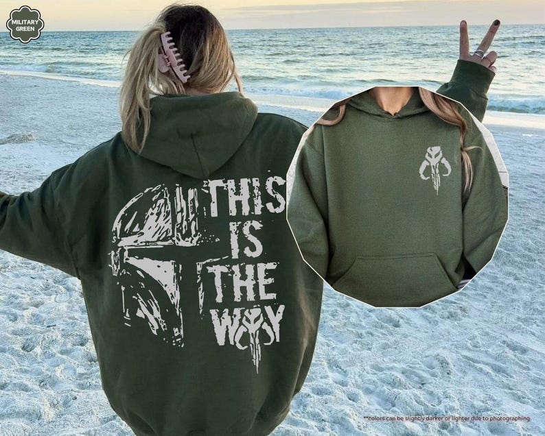 May include: A green hooded sweatshirt with a white graphic print of a Mandalorian helmet and the text "This is the Way".