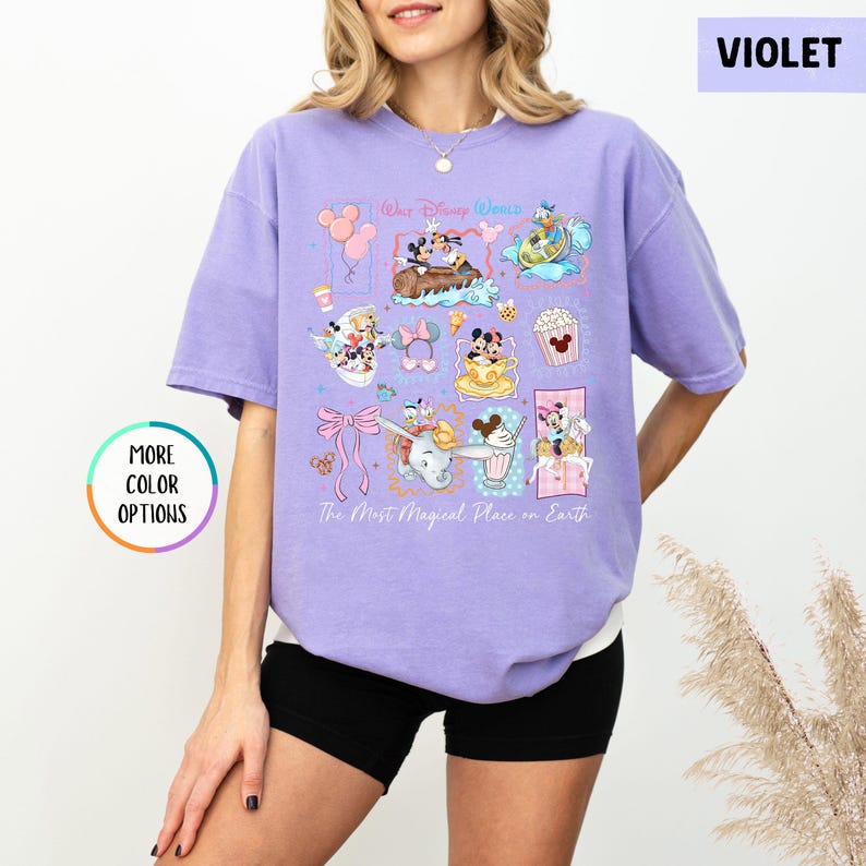 May include: A violet-colored t-shirt featuring a colorful graphic design with various Disney characters and icons. The shirt includes the text "Walt Disney World" and "The Most Magical Place on Earth". The shirt has short sleeves and a relaxed fit.