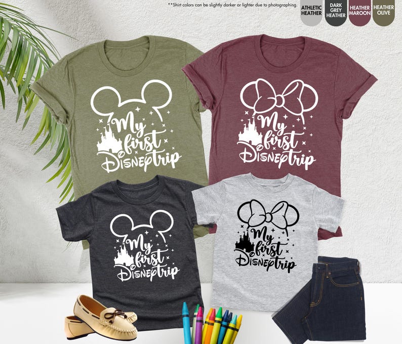 Pode incluir: Quatro camisetas com o texto "My first Disneptrip" em branco. As camisetas s&atilde;o de cores diferentes: verde, vinho, cinza e cinza escuro. Cada camiseta tem um design diferente: orelhas do Mickey Mouse, orelhas da Minnie Mouse e um castelo.