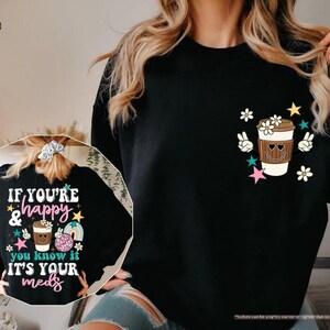 a woman wearing a black sweatshirt with a cup of coffee on it