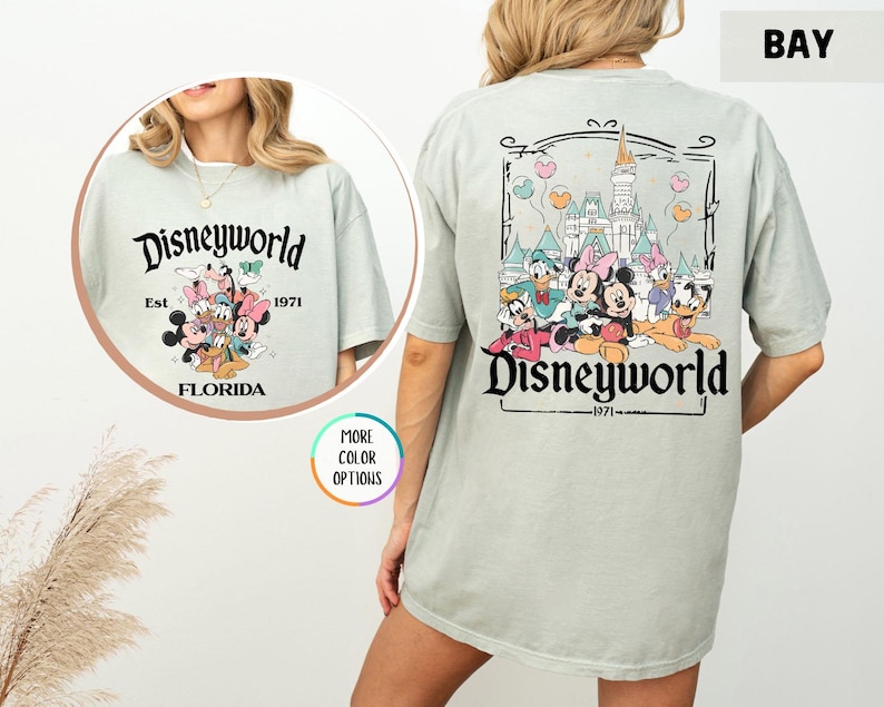Puede incluir: Camiseta verde claro con el texto "Disneyworld" y el a&ntilde;o "1971". La parte delantera de la camiseta tiene un gr&aacute;fico de Mickey y Minnie Mouse, Donald y Daisy Duck y Goofy. La parte trasera de la camiseta tiene el castillo de Cenicienta y los mismos personajes.