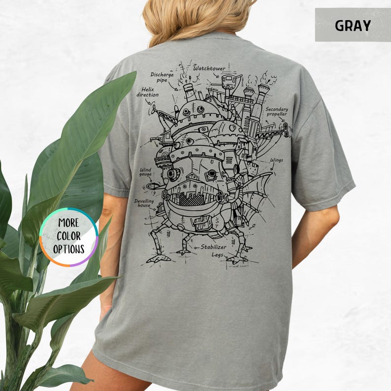 Op de afbeelding: Grijs T-shirt met een gedetailleerde zwart-wit illustratie van een mechanische structuur met labels zoals "Discharge pipe" en "Watchtower". Het shirt heeft ook de tekst "MORE COLOR OPTIONS" en "GRAY".